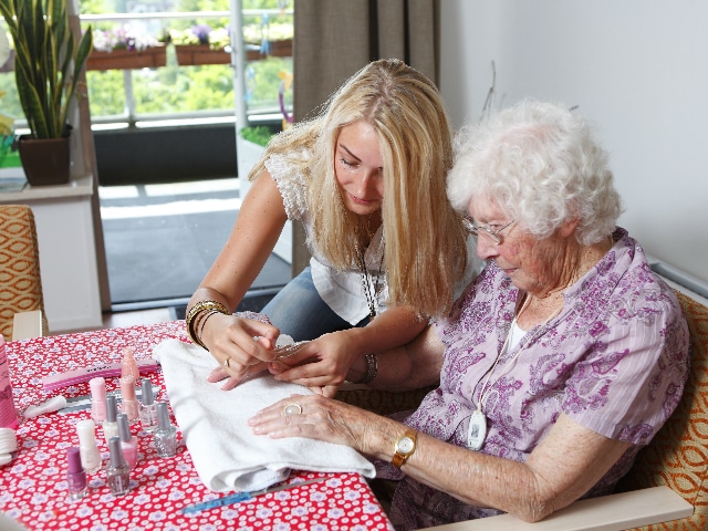 Vrouw lakt de nagels van een oudere dame