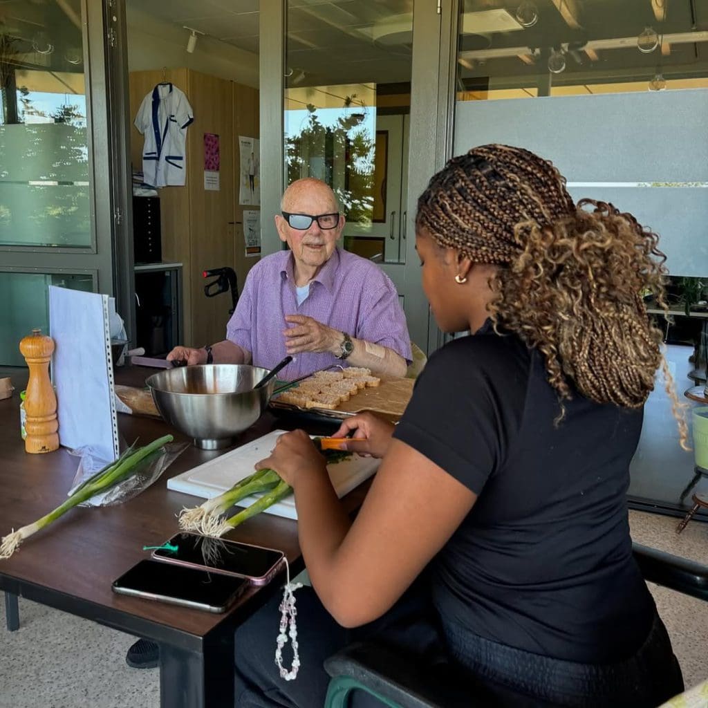Bewoners en medewerker koken samen in de huiskamer van een woonzorgcentrum